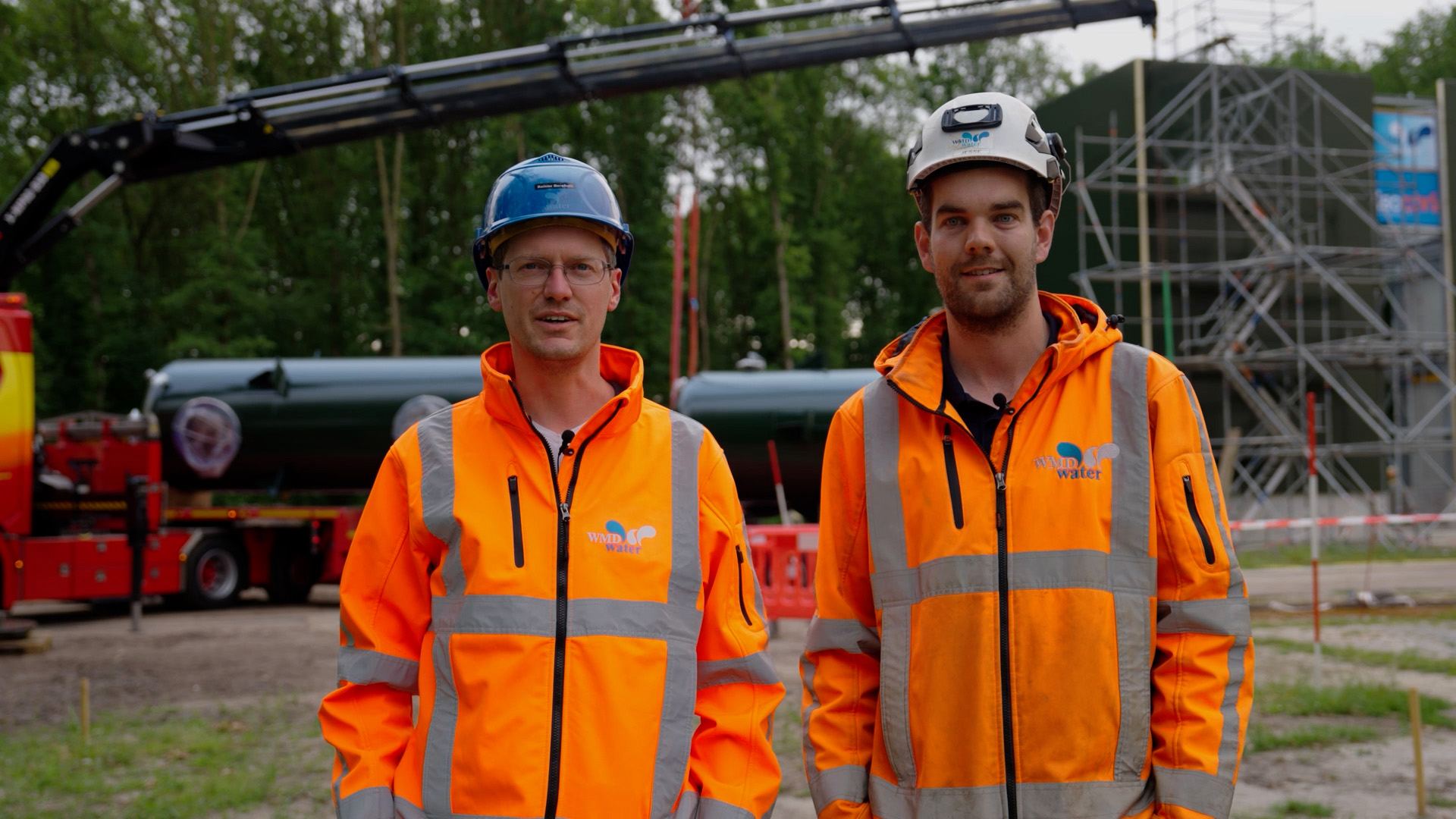 Twee medewerkers in werkkleding bij het hijswerk op locatie